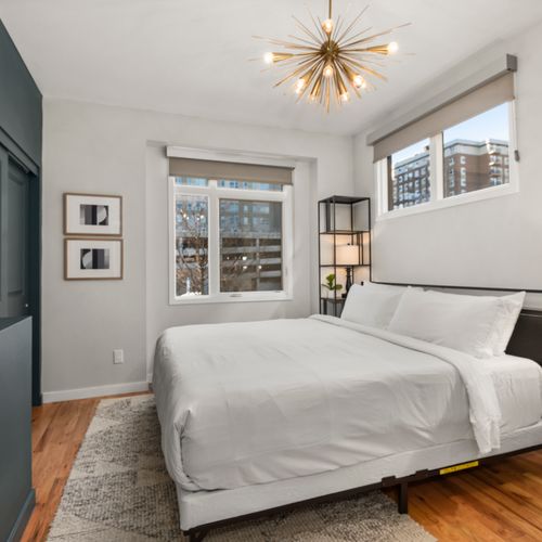 Calm bedroom featuring plush bedding, ample storage, and natural light throughout space