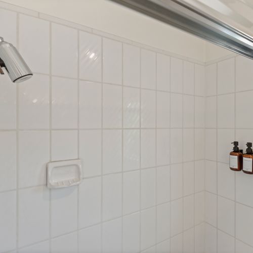 Sparkling white walls, rainfall showerhead, and a peaceful vibe for your morning routine.