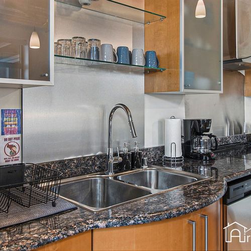 - double sink and granite countertops make meal prep and cleanup stylish and simple
- open shelving keeps cups and dishes within easy reach for a streamlined setup
- sleek design paired with modern fixtures adds to the industrial flair