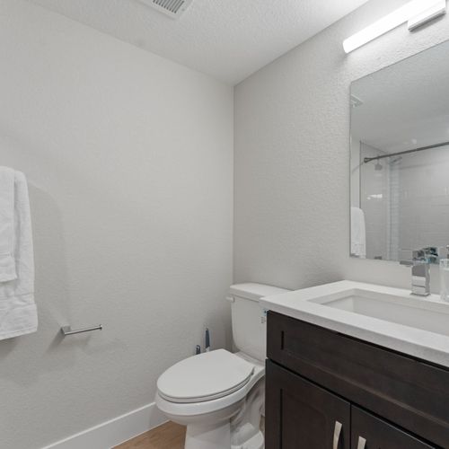 Fresh and simple, the all-white bathroom offers a sleek single vanity and an uncluttered design.