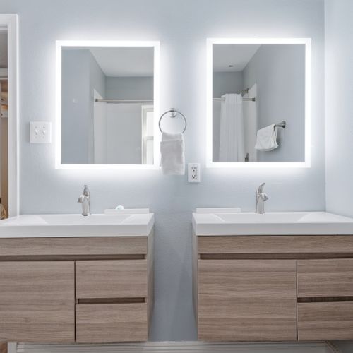 Freshen up at the double vanity w/ lit mirrors & clean, modern finishes.