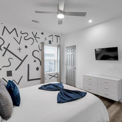 Unwind in this stylish bedroom, complete with bold mural accents and modern amenities. Relax with a wall-mounted TV and ample storage space for a comfortable stay.