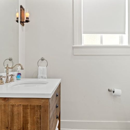 First bathroom vanity w/ sink & large mirror.