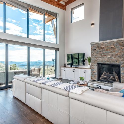 The living area features soaring loft windows with vaulted ceilings, a towering stacked-stone fireplace and 70" smart tv.