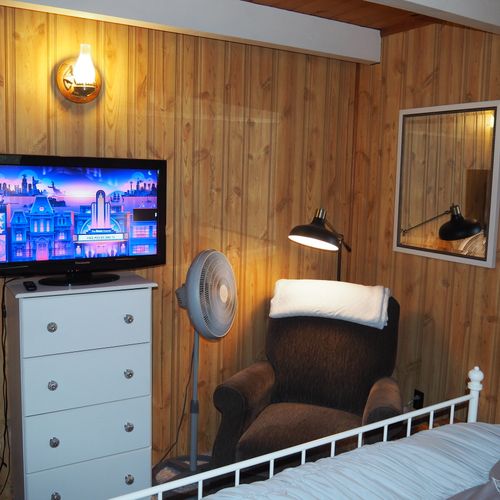 Bedroom #1 (main floor):  features a queen-size bed, chair, dresser, nightstands with lamps, fan, floor lamp, and its own television.