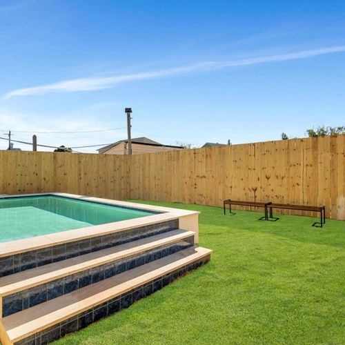 Spacious pool area w/ lush green lawn — plenty of room to lounge between dips.