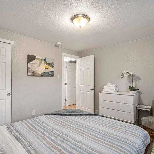- second view of queen bedroom showing modern white dresser, artwork, & fresh orchid
- warm wood floors & soft lighting make the room feel both polished & peaceful
- everything you need for a relaxed night’s rest & easy organization during your stay