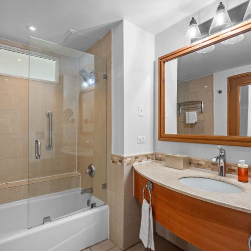 Sparkling clean and modern bathroom featuring a refreshing shower-tub combo, perfect for unwinding after a day of exploring