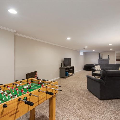 The lower level features a lounge space that doubles as a game room, providing ample space for everyone to unwind.