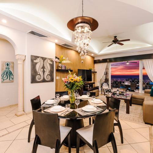 Formal dining with crystal chandelier, table for six, octopus and seahorse art, and open sightline to the balcony.