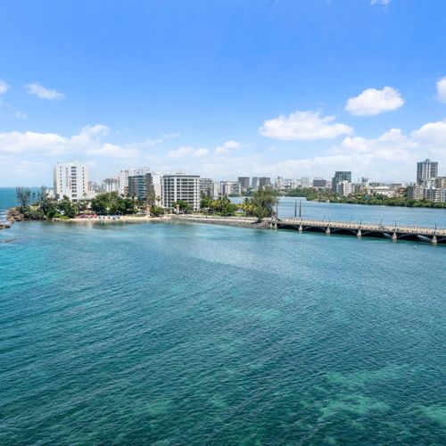 Witness the dynamic beauty of Condado from above, where clear waters, distant beaches, and the city skyline converge.