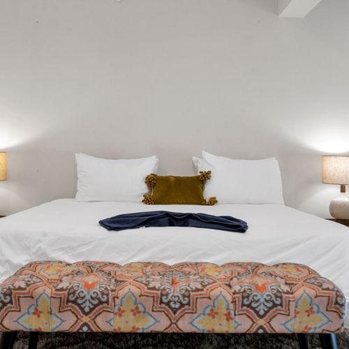 Clean lines, soft linens, and a touch of color give this bedroom a fresh, welcoming feel—ideal for couples or solo travelers.