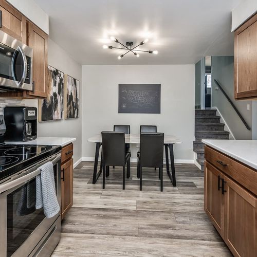 - stylish kitchen with wood cabinets stainless appliances and sleek countertops
- dining area for six beneath a bold light fixture and gallery wall accent
- warm flooring and open sightlines create flow and function throughout