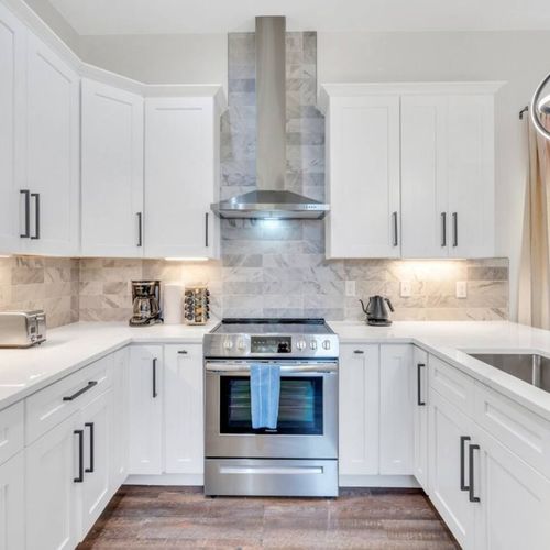Fully stocked kitchen w/ stainless appliances & sleek white cabinetry.