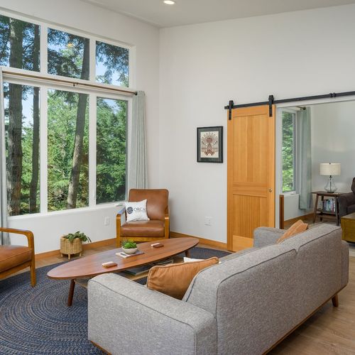 open living room concept with comfy seating and large windows to the towering trees outside.