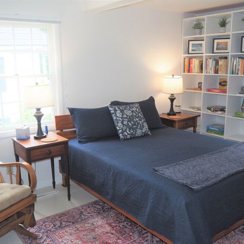 Bedroom #2 (main floor):  large and lovely bedroom with a queen-size bed, rocking chair, nightstands with lamps, two bookcases, a dresser, and a wardrobe.