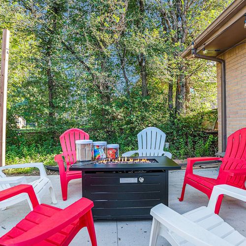 - vibrant patio hangout with red and white adirondack chairs circling a sleek fire pit
- surrounded by greenery for a secluded, peaceful evening under the stars
- perfect for cozy nights with s’mores, drinks, and great company