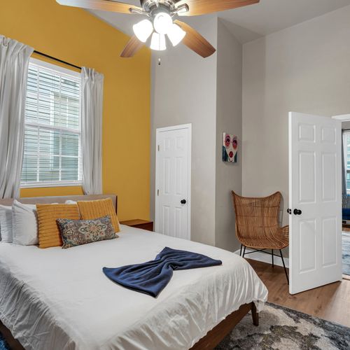 Sun-filled bedroom w/ yellow accents & a seating area to unwind.