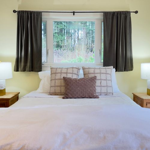 Drift off in a calm, comfortable bedroom with soft white linens, cozy pillows, and warm bedside lamps. Forest views just outside the window create a peaceful setting for quiet nights and relaxed mornings.