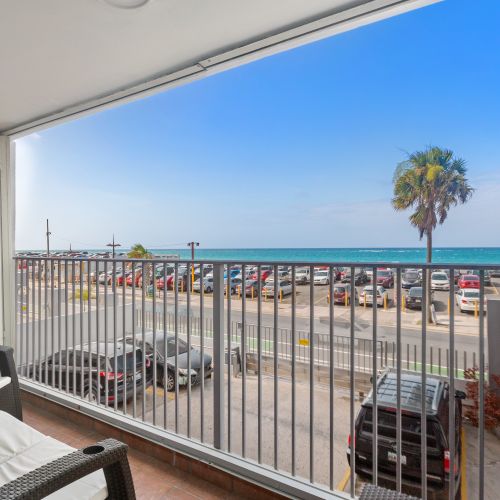 Balcony with direct ocean view, outdoor seating, and panoramic vista of the beach and horizon, ideal for relaxation.