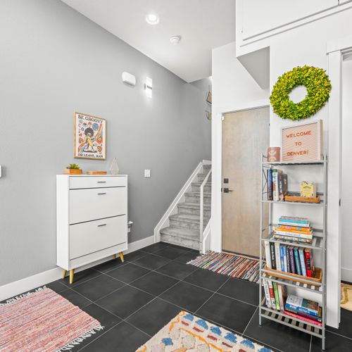 Bright entryway with thoughtful organized storage, books, and easy access throughout home here