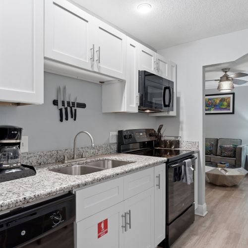 Sleek kitchen w/ granite counters, sink & full appliances.