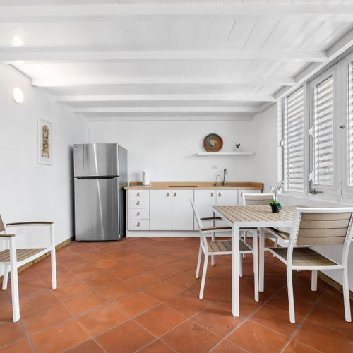 This space features a stylish dining set and a practical kitchenette equipped with a full-sized stainless steel refrigerator and ample counter space.