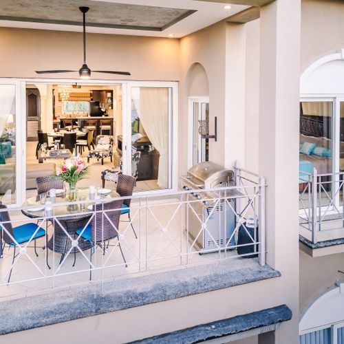 Covered balcony with ceiling fan, round dining table, and lounge chair overlooking pool and Tamarindo Bay.