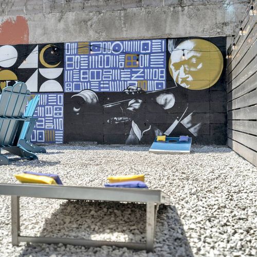 Backyard cornhole & bold mural backdrop — where good times happen naturally.