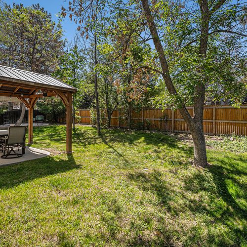 Your morning coffee spot: shaded patio overlooking a tranquil, tree-lined yard.