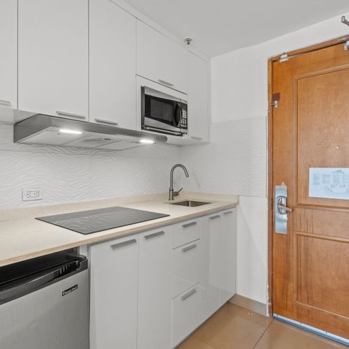 Enjoy the convenience of a compact yet complete kitchen, thoughtfully designed with everything you need for a comfortable stay, including a refrigerator, stovetop, and ample counter space.