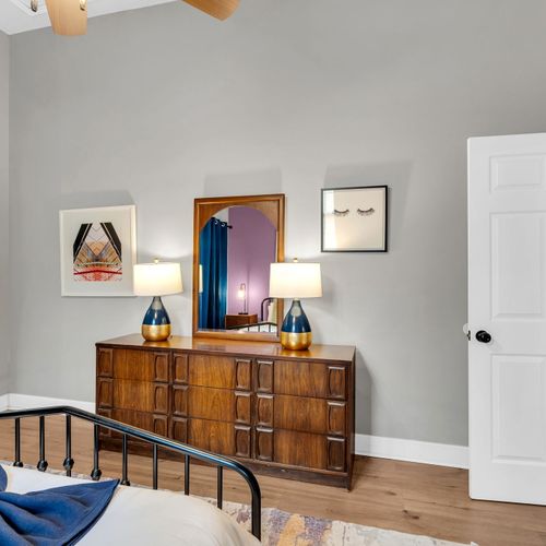 Warm wood dresser w/ eclectic art — a charming corner that feels curated & personal.