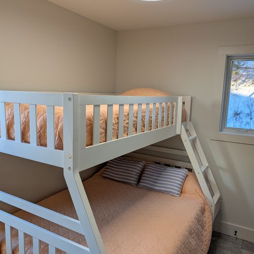 BEDROOM #2 (MAIN FLOOR):  Features a twin-on-full bunk bed, trundle bed that slides in below the bunk bed, ceiling fan with safety guard, dresser, mirror, closet, and lamp.