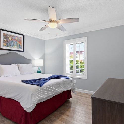 Airy bedroom w/ ceiling fan & soft natural light for restful nights.