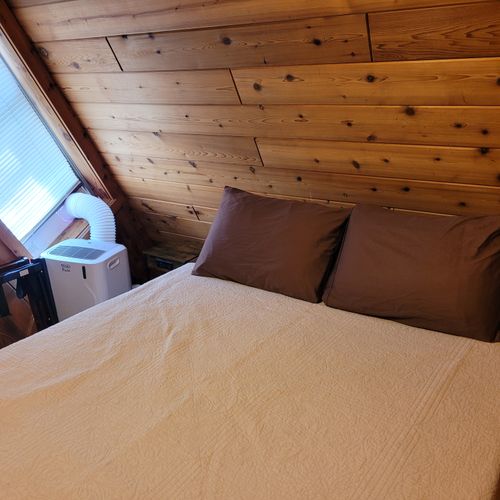 Bedroom #2 (main floor):  features a queen-size bed, portable a/c unit, closet, and drawers.