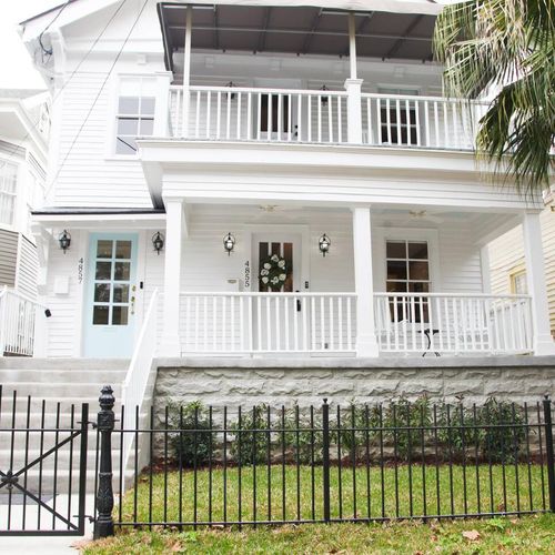Classic two-story home exterior w/ wraparound balcony & iron fence.
