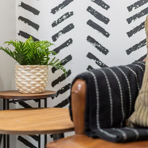 - touch of greenery in a woven basket adds freshness and natural charm to the space
- layered side tables offer both function and design, perfect for drinks or books
- textured pillows and throws complement the bold wall pattern for cozy character