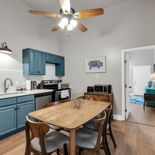 Fully equipped kitchen w/ teal cabinets & a wooden dining table for shared meals.