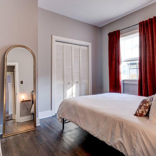 Sun-drenched bedroom w/ arched mirror & shuttered windows for a breezy feel.