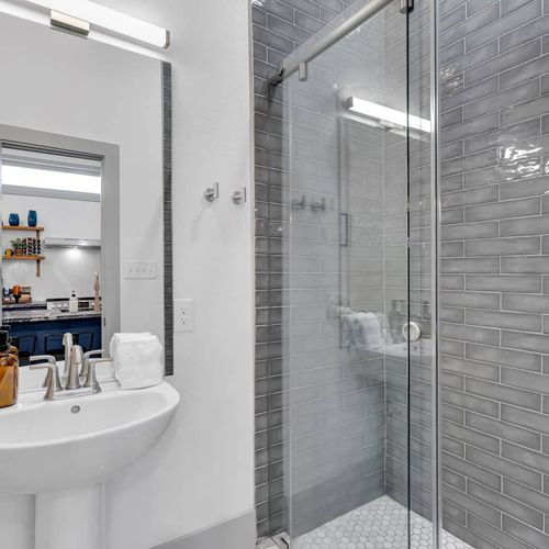 Sleek bathroom w/ gray subway tiles, tub & shower combo, & clean modern finishes.