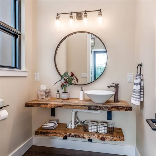 - unique bathroom features a live edge wood vanity and round mirror accent
- vessel sink and industrial style lighting bring together mountain and modern
- thoughtful design and open shelving make it both charming and functional