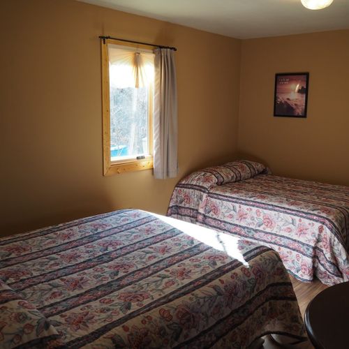 Main room:  features two double beds, small dining table with chairs, and a sink / kitchenette.