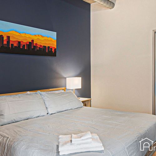 - rest easy in a plush king size bed set beneath a striking skyline canvas and bold blue wall
- clean white linens and soft lighting offer a calm and stylish retreat
- modern industrial bedroom that’s perfect for winding down after city adventures