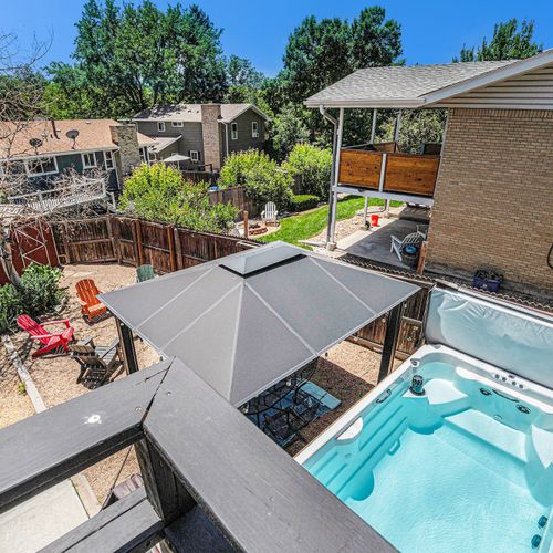 The backyard view from the balcony showcases a serene scene with a spa pool and a fenced-in yard, combining relaxation and security in a tranquil outdoor setting.