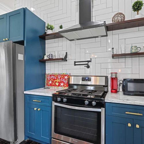 Sleek kitchen corner w/ a gas range, teal cabinets & classic white subway tile backsplash.