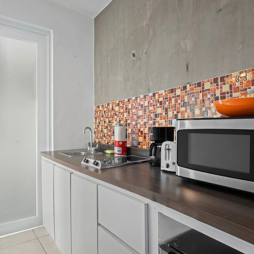 This compact yet stylish kitchen space features modern appliances and a vibrant backsplash, ideal for preparing your favorite meals with flair.