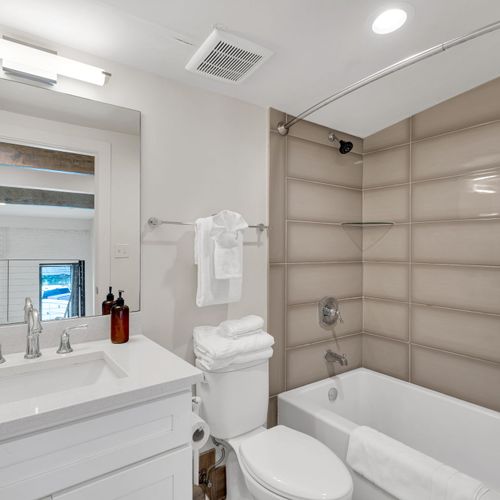 Well-lit bathroom w/ sink & shower — everything you need, right at hand.