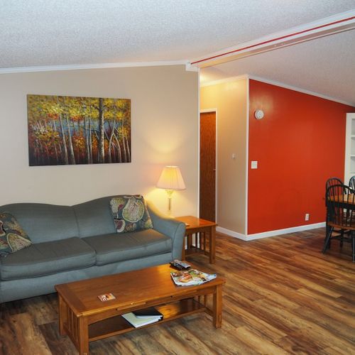 This photo shows part of the living room, the hallway that leads to bedrooms #2 and #3 and the second bathroom, and it also shows the dining area.