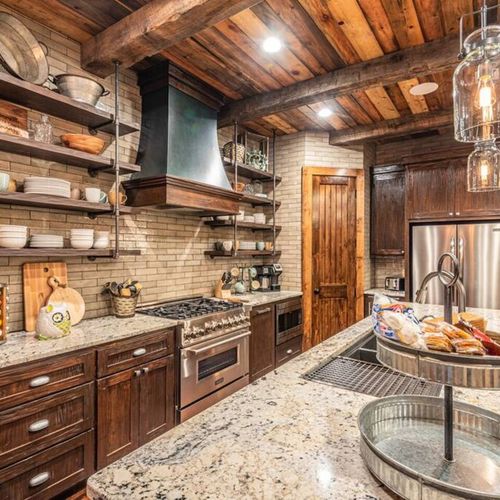 The kitchen houses stainless steel appliances and floating shelves.