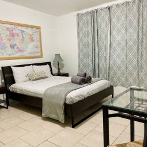Rest and recharge in our spacious Main Bedroom, featuring a comfortable Queen Size Bed, ample closet space, a dedicated work area, and refreshing air conditioning for your ultimate comfort.